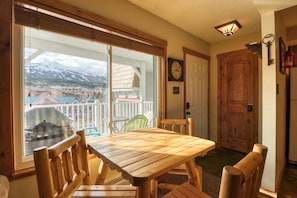 Enjoy meals and social gatherings in this room with a large table and chairs, offering a scenic view of the surrounding mountains.