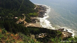 Paisagem costeira com uma estrada serpenteando pela praia, rodeada por floresta densa.
