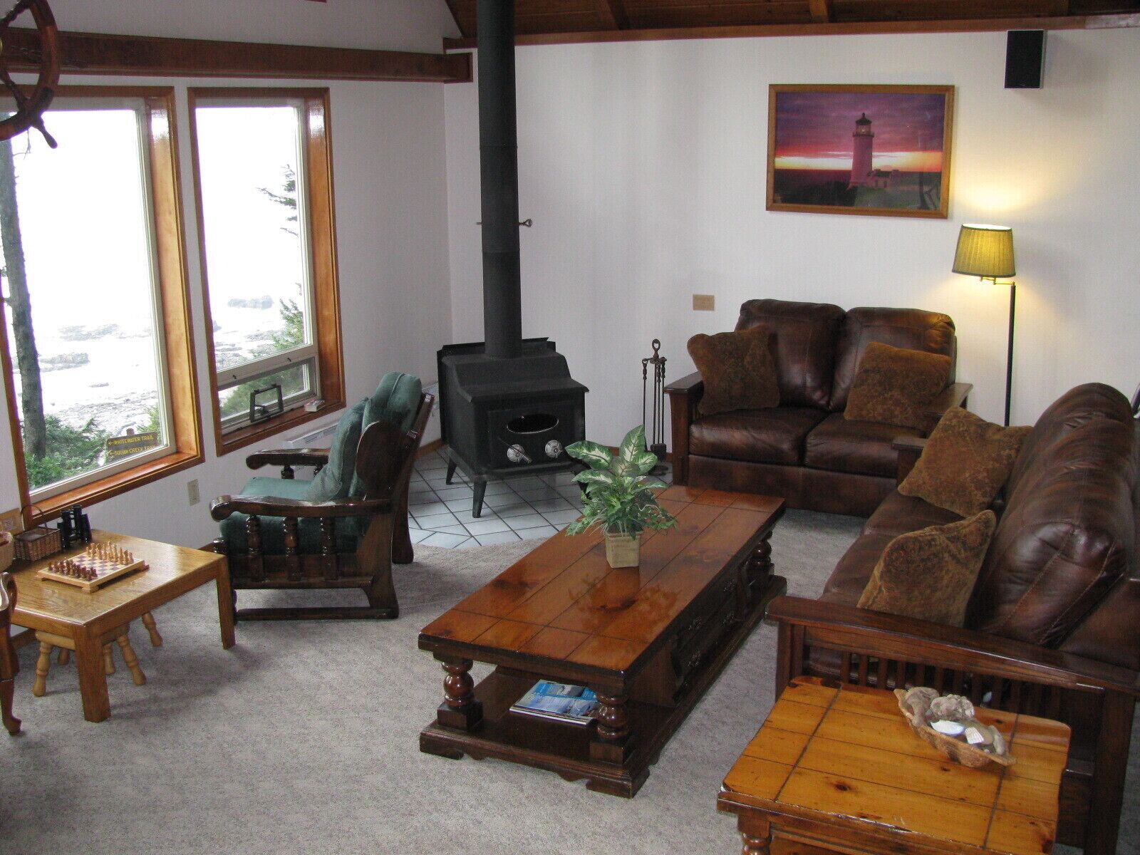 Un salon chaleureux avec une cheminée, un canapé en cuir, une table basse en bois et une vue sur l’extérieur.