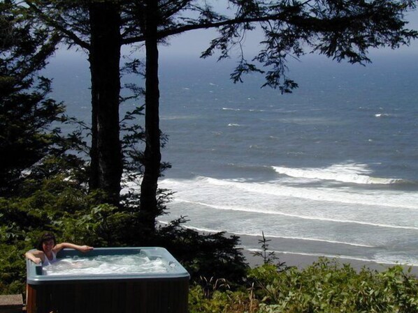 Un bain à remous avec vue sur l’océan et les arbres.