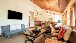 A living room with a sofa, a coffee table, a fireplace, and a dining area in the background.