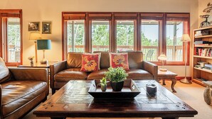 A living room with a brown leather sofa, a wooden coffee table with a tray, and a bookshelf.