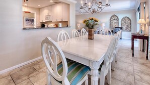 A dining area with a white table, chairs, and a chandelier. - Pet Friendly ~ Golf Cart~ Private Patio (Destin)