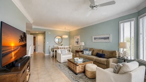 A living room with a TV, a ceiling fan, a dining area with chairs and a table, and a sofa. - 2403 SeaCrest-4th Floor/ Ocean Views & Newly Updated (Hilton Head Island)