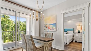 A dining area with a glass-top table, wicker chairs, and a chandelier.