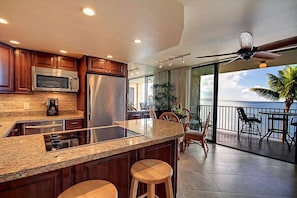 A modern kitchen with granite countertops, stainless steel appliances, and a large island with stools.