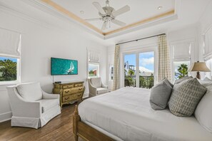 A bedroom with a large bed, a ceiling fan, a TV, and a view of the outdoors. - Gulf Views & Private Pool Just 105 Feet From Beach Access- 30A Mojo (Santa Rosa Beach)