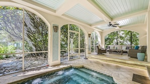 A spa area with a hot tub, seating, and large windows overlooking a garden.