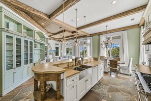 Una cocina espaciosa con una isla grande, vigas de madera y suelo de piedra.