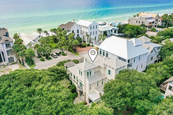 An aerial view of a coastal residential area with multiple houses, a clear view of the ocean, and a marked location on a house. - Gulf Views & Private Pool Just 105 Feet From Beach Access- 30A Mojo (Santa Rosa Beach)