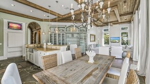 A spacious kitchen with white cabinetry, a wooden dining table, and a chandelier.