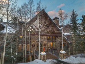 Un lodge con facciata in pietra, balconi in legno e ingresso innevato.