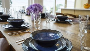 A dining table set with blue bowls, silverware, and clear glasses. - Magnolia: 7 BR Beachfront Home - Pet Friendly, Priv. Pool, Sleeps 24! (Cape San Blas)
