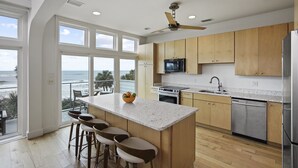A modern kitchen with a large island, wooden cabinets, stainless steel appliances, and a view of the ocean. - Magnolia: 7 BR Beachfront Home - Pet Friendly, Priv. Pool, Sleeps 24! (Cape San Blas)