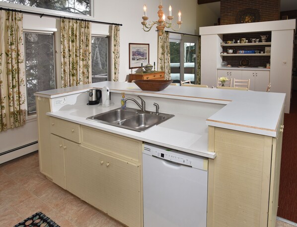A compact kitchen with a sink, a dishwasher, and a wooden bowl on the counter.