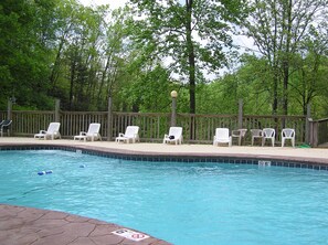 A swimming pool with white lounge chairs and a wooden deck. - Cabin w/Amazing Mountain Views-Hot Tub-Game Room (GATLINBURG)