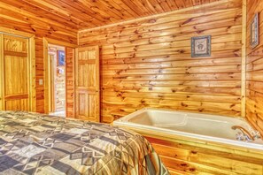A wooden cabin room with a bed, a wooden wall, and a bathtub. - Cabin w/Amazing Mountain Views-Hot Tub-Game Room (GATLINBURG)