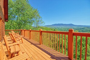 A wooden deck with lounge chairs and a railing overlooking a mountainous landscape. - Cabin w/Amazing Mountain Views-Hot Tub-Game Room (GATLINBURG)