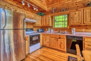A wooden cabin-style kitchen with a stainless steel refrigerator, oven, microwave, and dishwasher. - Cabin w/Amazing Mountain Views-Hot Tub-Game Room (GATLINBURG)