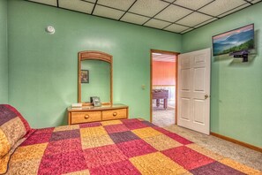 A bedroom with a large bed, a dresser, a mirror, and a door leading to another room. - Cabin w/Amazing Mountain Views-Hot Tub-Game Room (GATLINBURG)