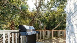 A barbecue grill on a wooden deck with a white fence and lush greenery in the background. - Northern Exposure | Close to Beach + Outdoor Space (Tybee Island)