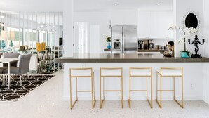 A modern kitchen with a central island, bar stools, and a dining area with a patterned rug. - Regency Modern - Indian Canyons Hollywood Regency! (Palm Springs)