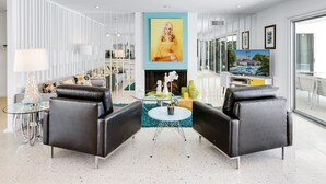A modern living room with a fireplace, a television, and a dining area with a glass table and chairs. - Regency Modern - Indian Canyons Hollywood Regency! (Palm Springs)