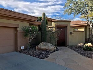 Propiedad residencial con garaje, un cactus grande y un camino de piedra.