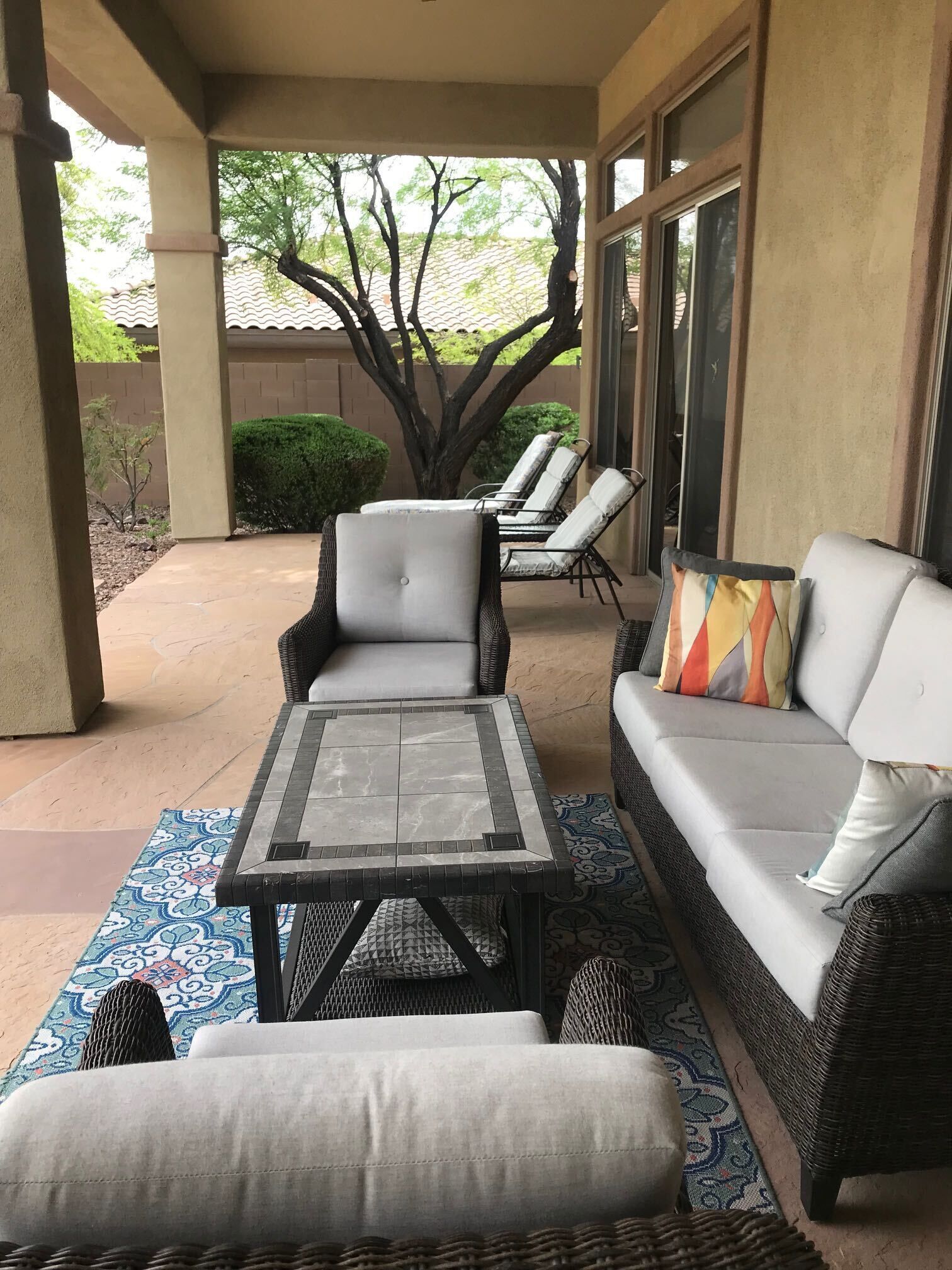 A covered patio area with a sofa, two chairs, and a small table.