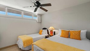 A hotel room with two single beds, a ceiling fan, a nightstand with a lamp, and a window with curtains. - Oceanview Oasis Walk to Shops & Dining: Kamaole Nalu #303 Convenience & Charm! (Kihei)