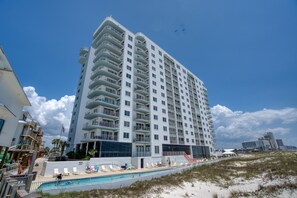 A tall, multi-story hotel with a pool area and beach access.