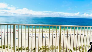 A beach view from a balcony with a railing, sandy beach, and ocean. - Lighthouse 1405 (Gulf Shores)