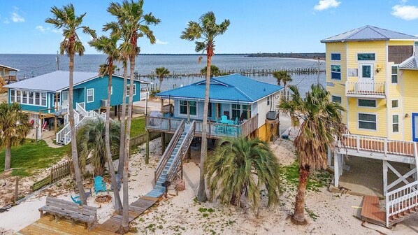 A beachfront property with multiple buildings, including a house with a blue roof and a yellow building with a balcony.