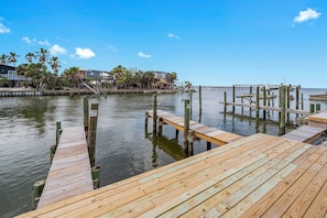 A wooden dock extending into calm water, surrounded by a dock area with wooden posts and a clear sky.