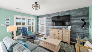 A living room with a sofa, a coffee table, a TV, and a wooden cabinet. - Tortuga Bay | 2BR/1BA Waterfront Home | Pet-friendly Fort Morgan Retreat (Gulf Shores)