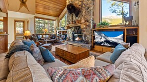 Una sala de estar acogedora con chimenea de piedra, asientos cómodos y un televisor grande.