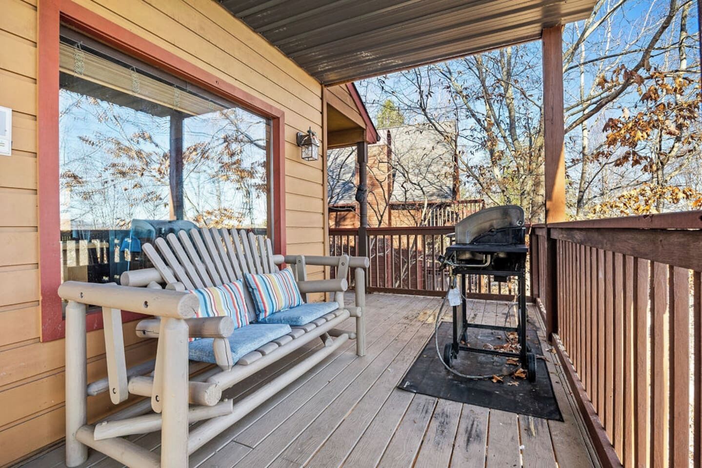 A wooden deck with a rocking chair and a grill.