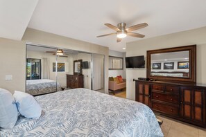 A bedroom with a bed, a dresser, a television, and a ceiling fan.