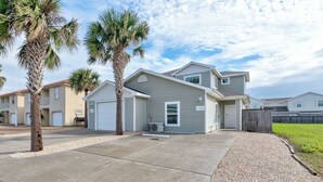 A residential building with a garage, a covered patio, and a fenced yard. - Updated Coastal Duplex | Heated Pool & Walk to the Beach (Corpus Christi)