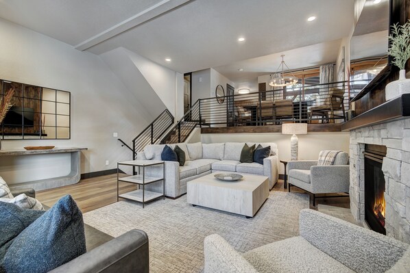 A spacious living area with a modern fireplace, a staircase, and a dining area. - Remodeled Fall 2024! Quick walk to Snowflake Lift & Main Street (Breckenridge)