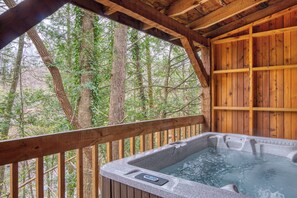 A hot tub in a wooden cabin with a view of a forest.