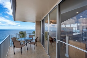 Ein Balkon mit Tisch und Stühlen mit Blick auf das Meer.