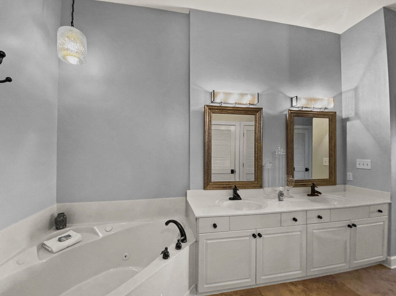 A modern bathroom with a large bathtub, two sinks, and two mirrors.