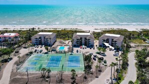 Un hôtel situé en bord de mer, composé de plusieurs bâtiments, doté d’un court de tennis et d’une piscine.