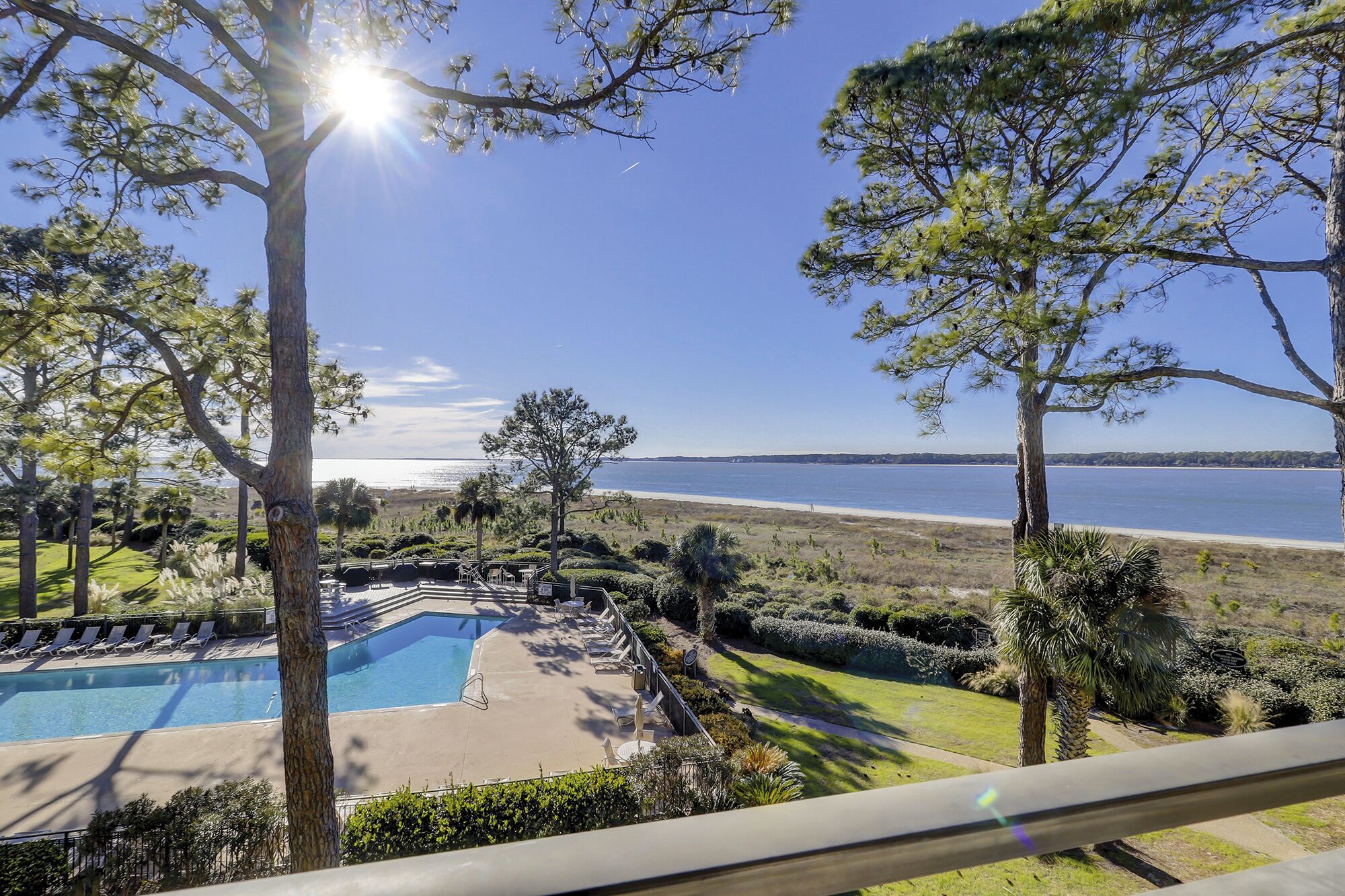 A pool area with a view of the beach and ocean.