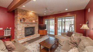 A living room with a stone fireplace, a television, and a sofa. - Spacious Mountain Escape w/ Hot Tub and Fireplace (OAKLAND)