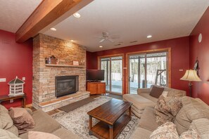 A living room with a stone fireplace, a television, and a sofa.