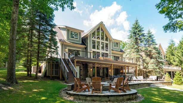 A large, multi-story house with a covered patio area, outdoor seating, and a staircase leading to the upper levels. - Spacious Mountain Escape w/ Hot Tub and Fireplace (OAKLAND)