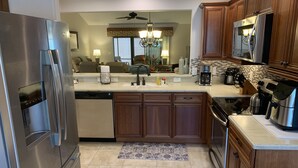 A modern kitchen with stainless steel appliances, wooden cabinets, and a tiled backsplash. - Beautiful 3/2 Sm Dog Friendy home w/WiFi! Central Location to each town! (The Villages)