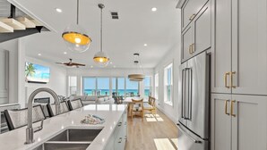Een moderne keuken met een groot eiland, roestvrijstalen apparatuur en uitzicht op de oceaan.